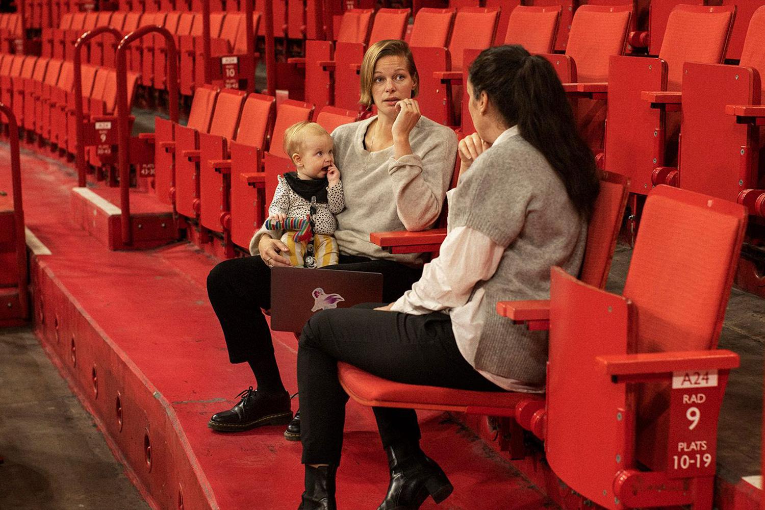 Two women having a meeting in a theatre with a baby.