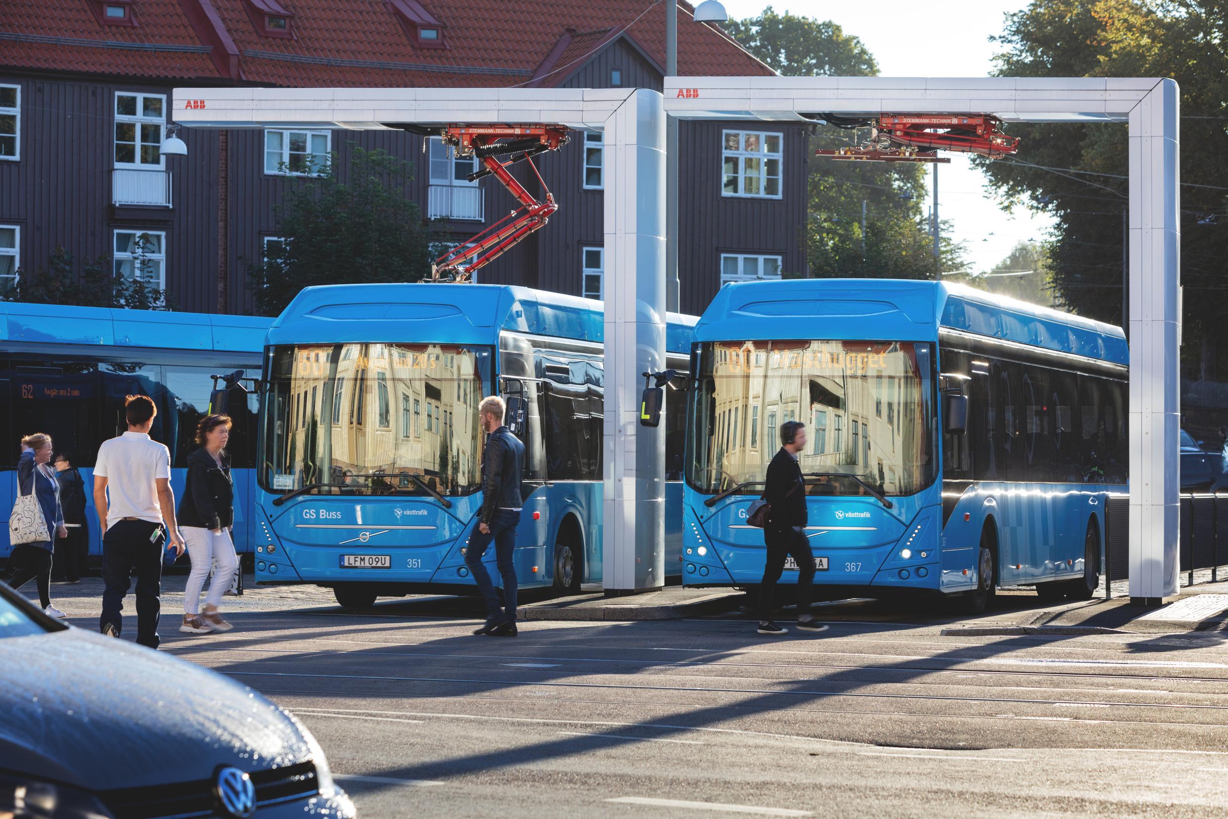 Two buses parked at an electric charging station.