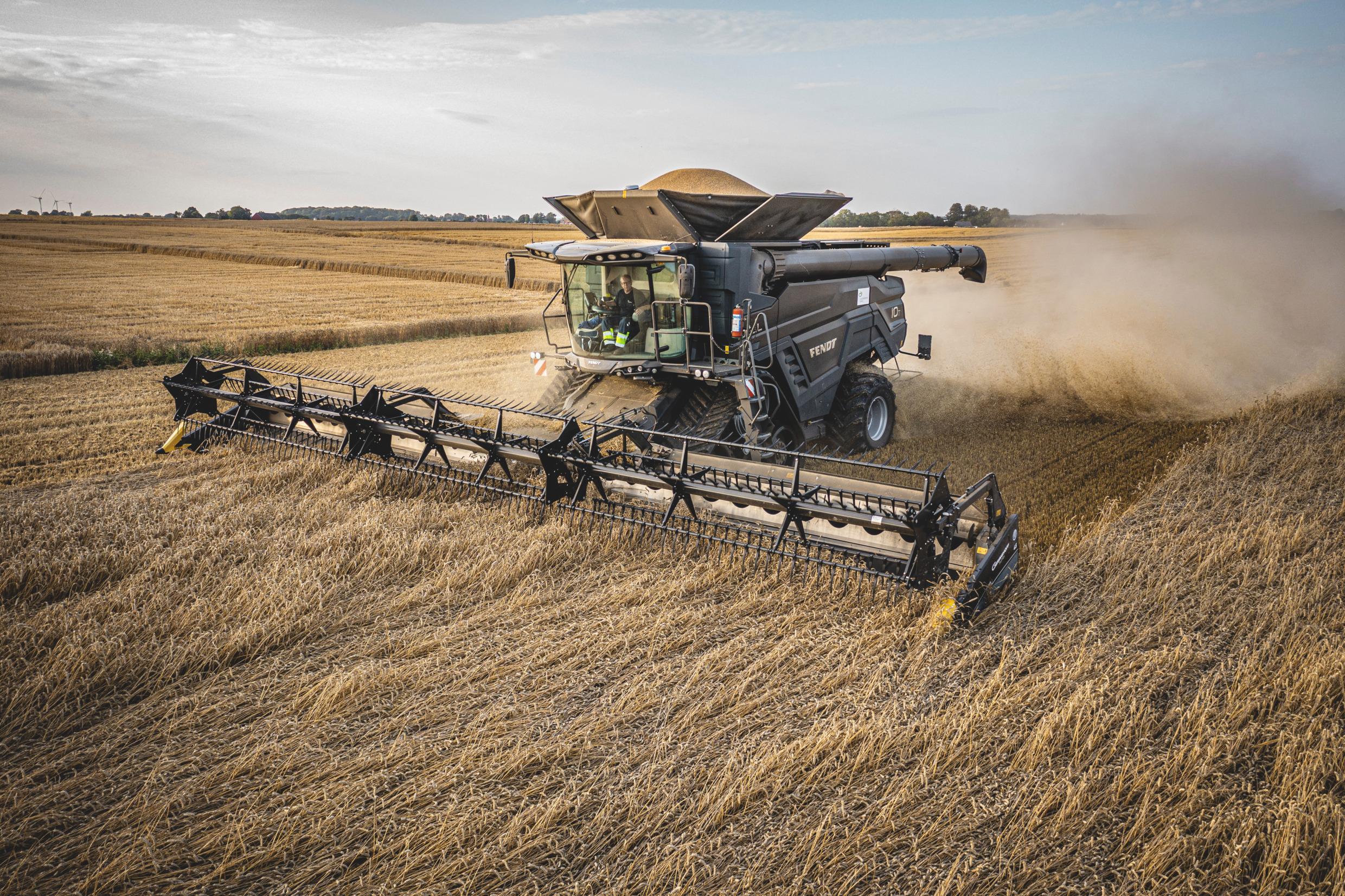 A threshing machine is in use on farmland.