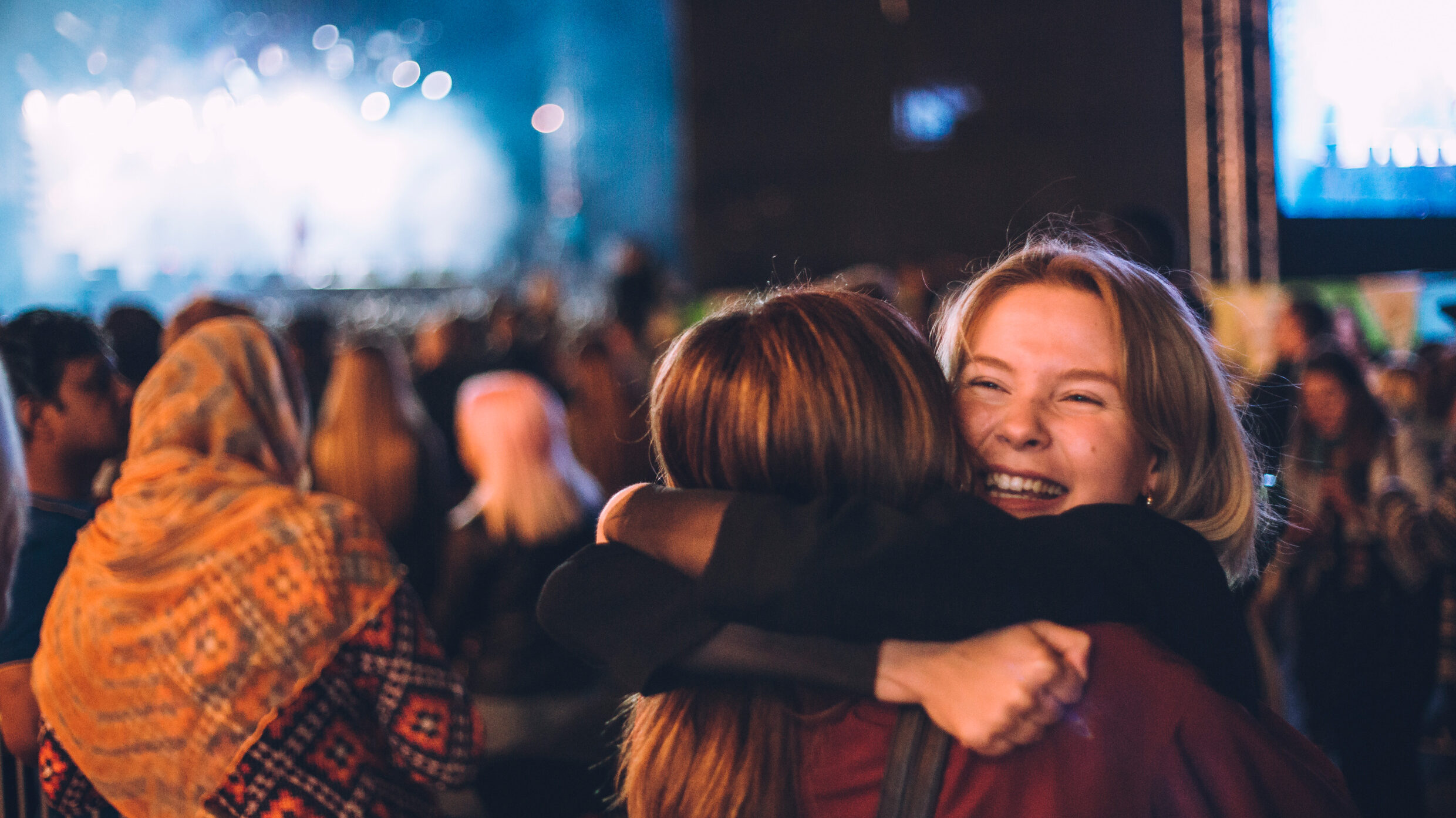 Two friends hugging at a music festival.