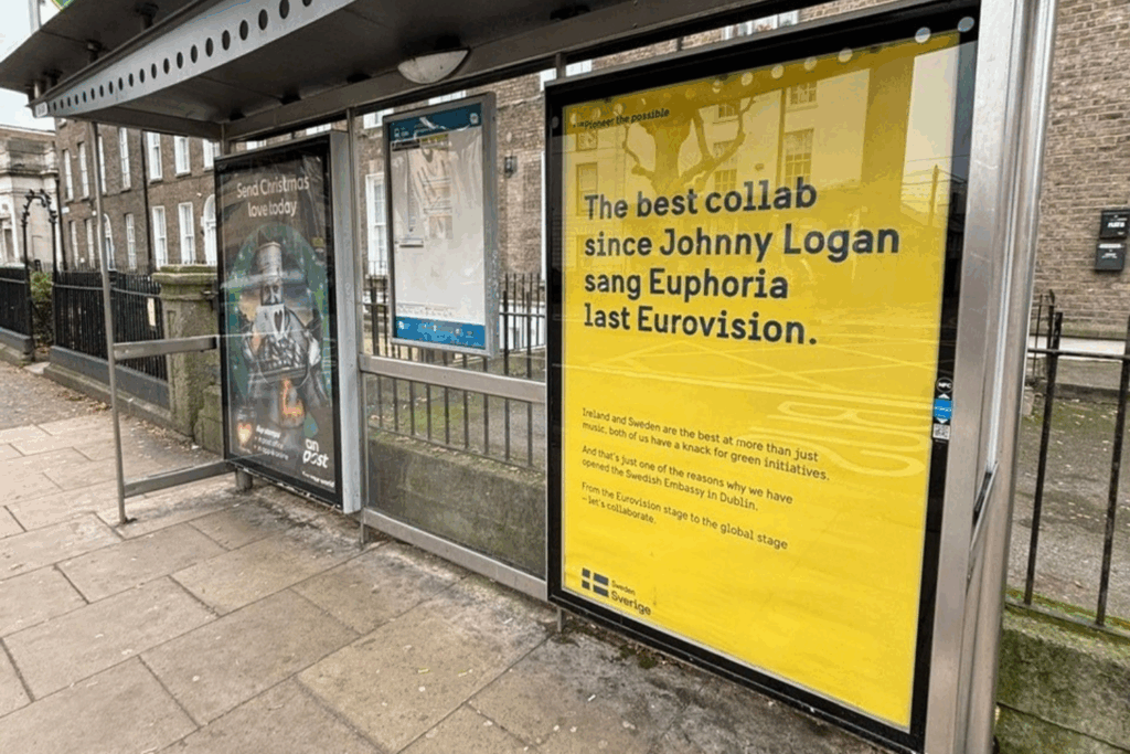 An ad at a bus station saying "The best collab since Johnny Logan sang Euphoria last Eurovision"